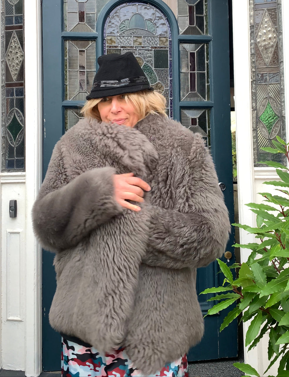 Rebecca walking out of front door in elama long sleeve shirt dress with hat a sheepskin coat