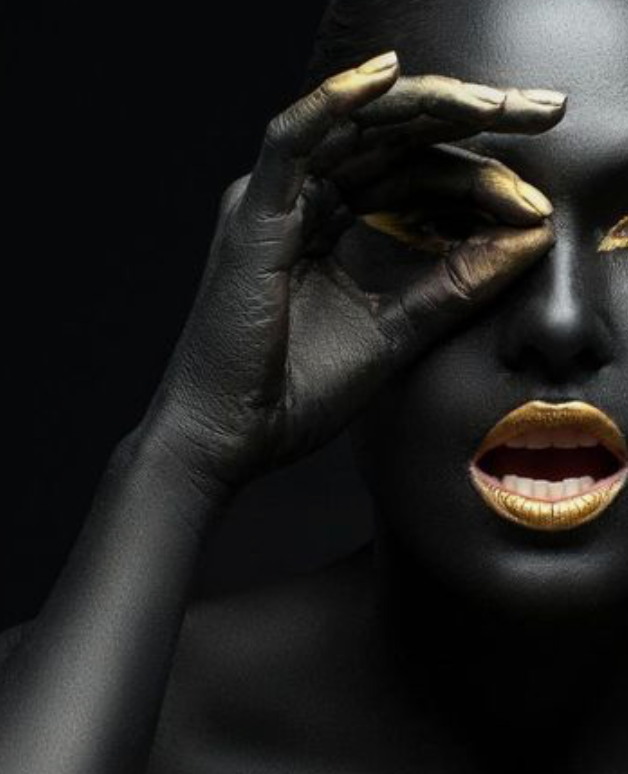 woman looking through fingers with gold nails and lipstick