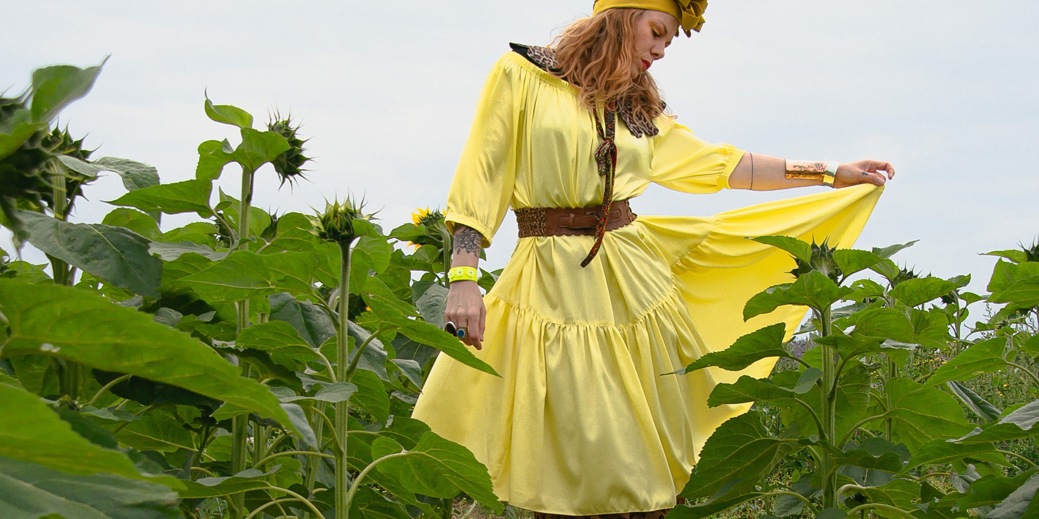 woman standing in sunflower field wearing ausus in sherbet yellow