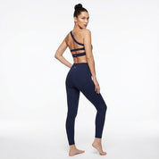 Woman wearing a navy blue sports bra and leggings on a white background