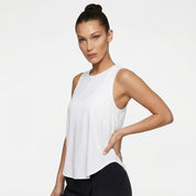 Woman wearing a white sleeveless top against a plain background