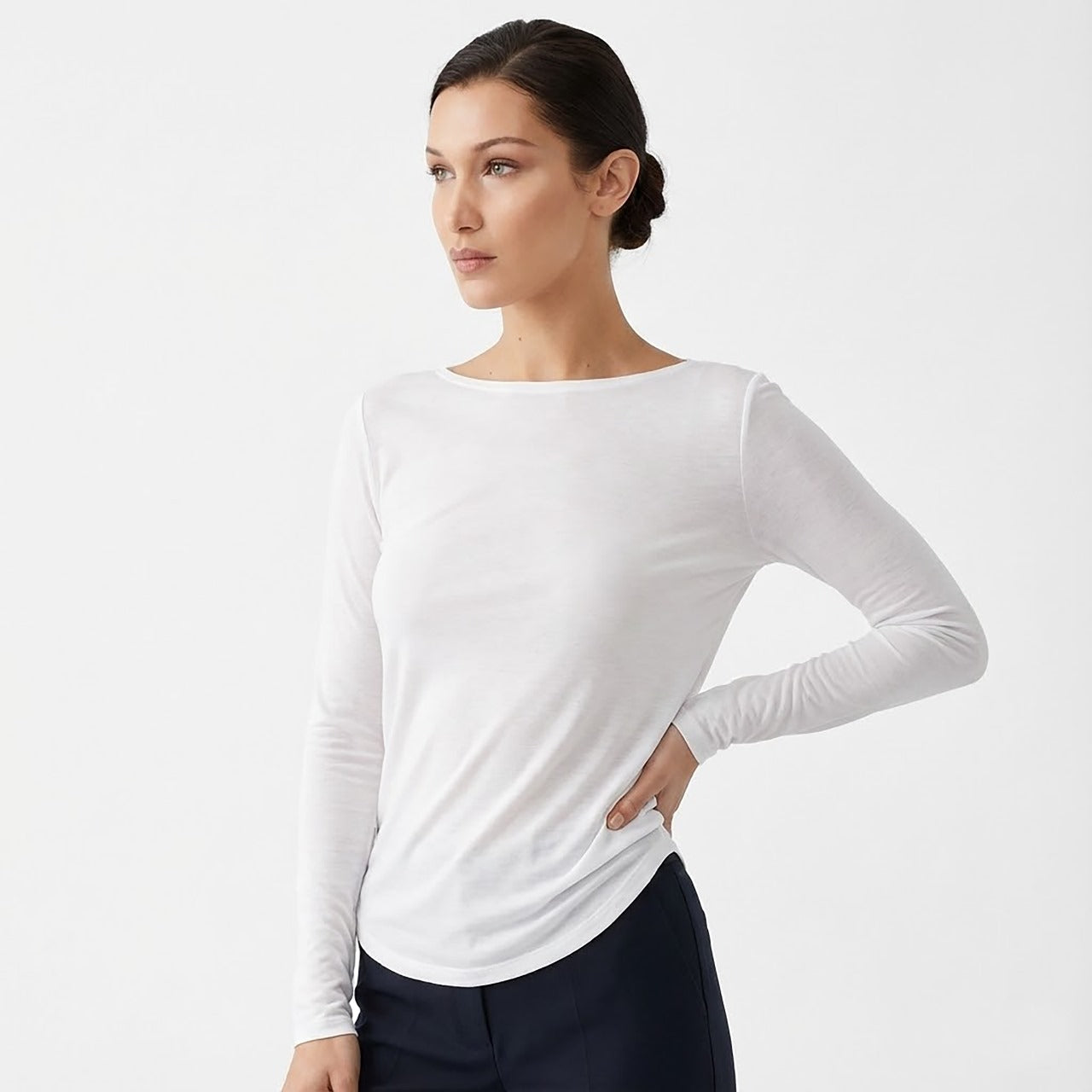 Woman wearing a white long-sleeve top against a light gray background