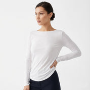 Woman wearing a white long-sleeve top against a light gray background