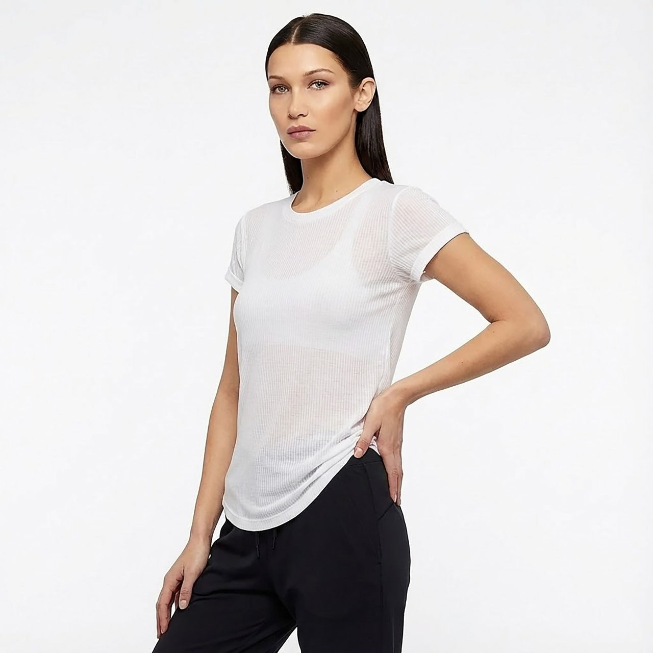 Woman wearing a white t-shirt and black pants on a plain background