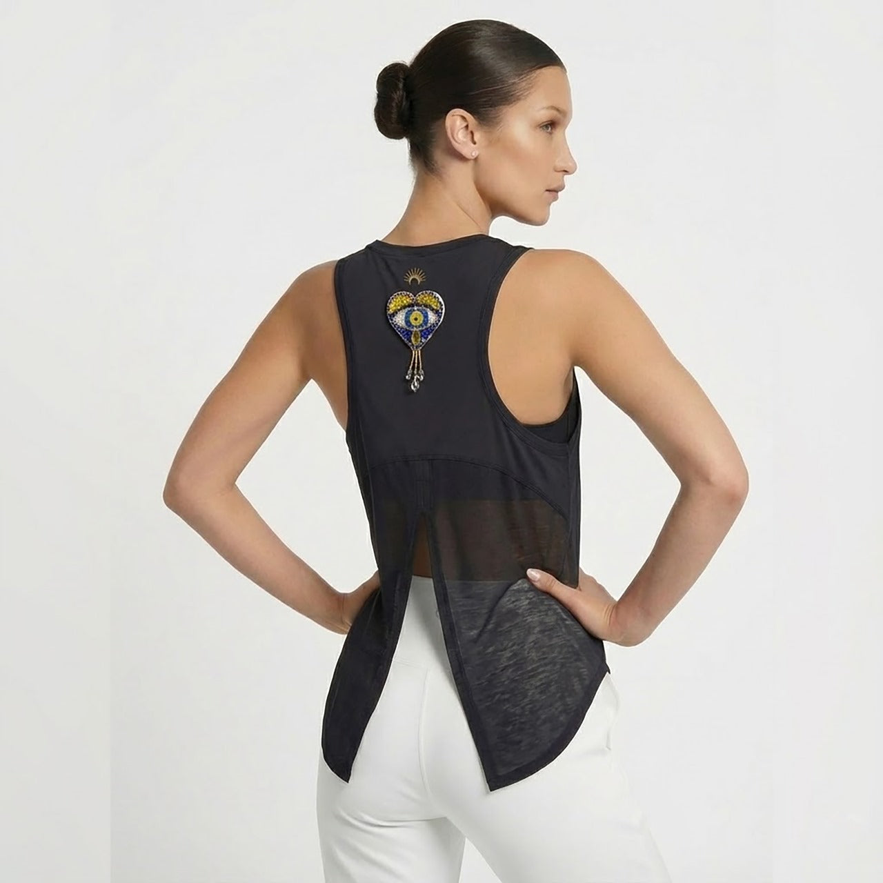 Woman wearing a black sleeveless top with a unique design on the back against a white background