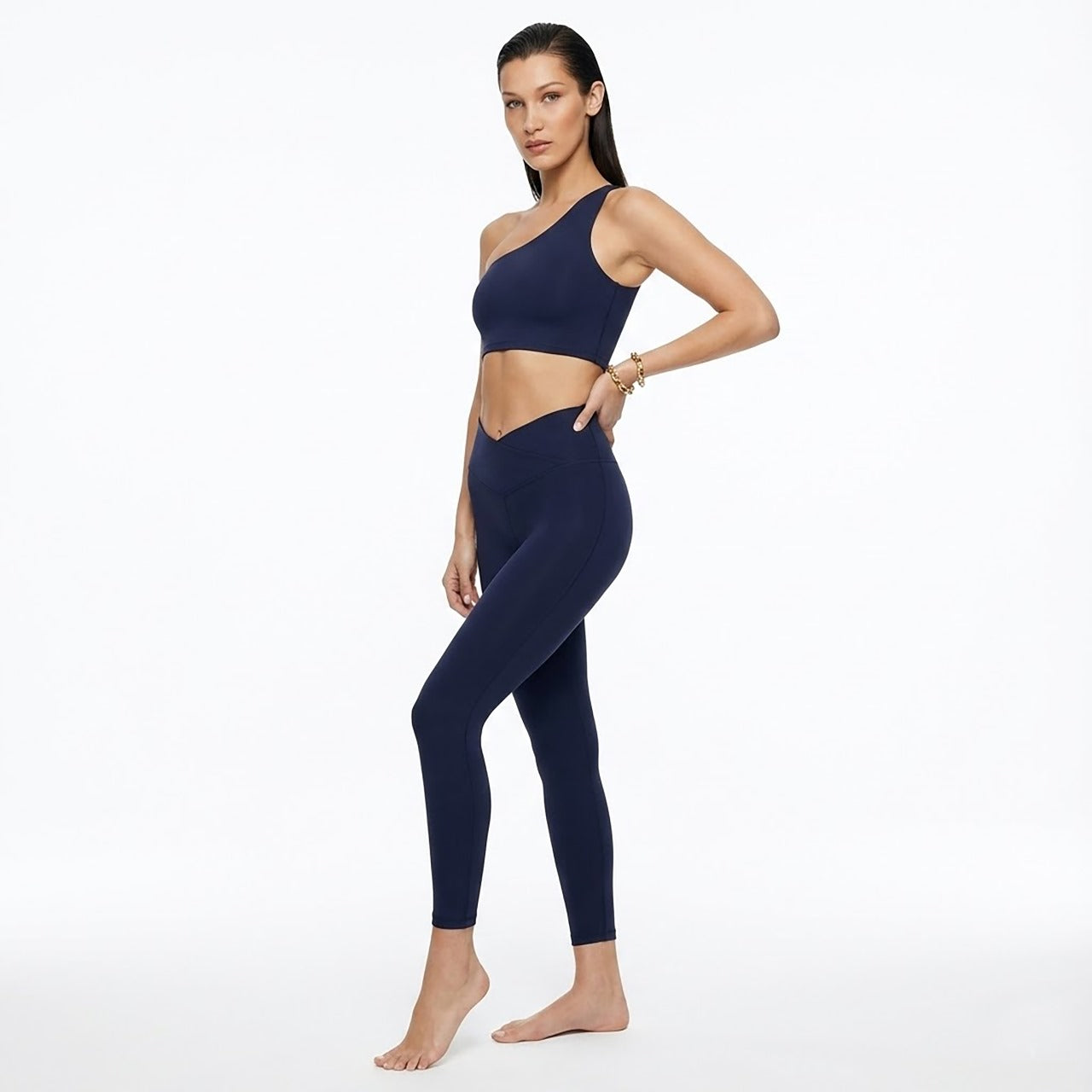 Woman wearing a navy blue sports bra and leggings on a white background