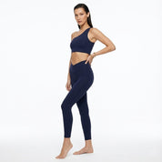 Woman wearing a navy blue sports bra and leggings on a white background