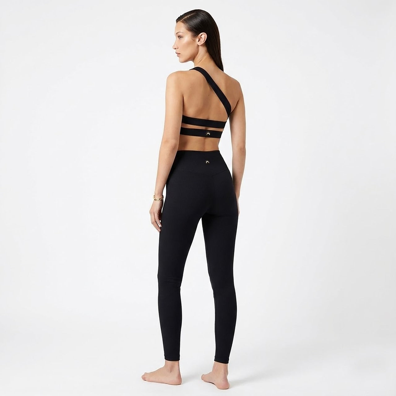 Person wearing a black sports bra and leggings set on a white background