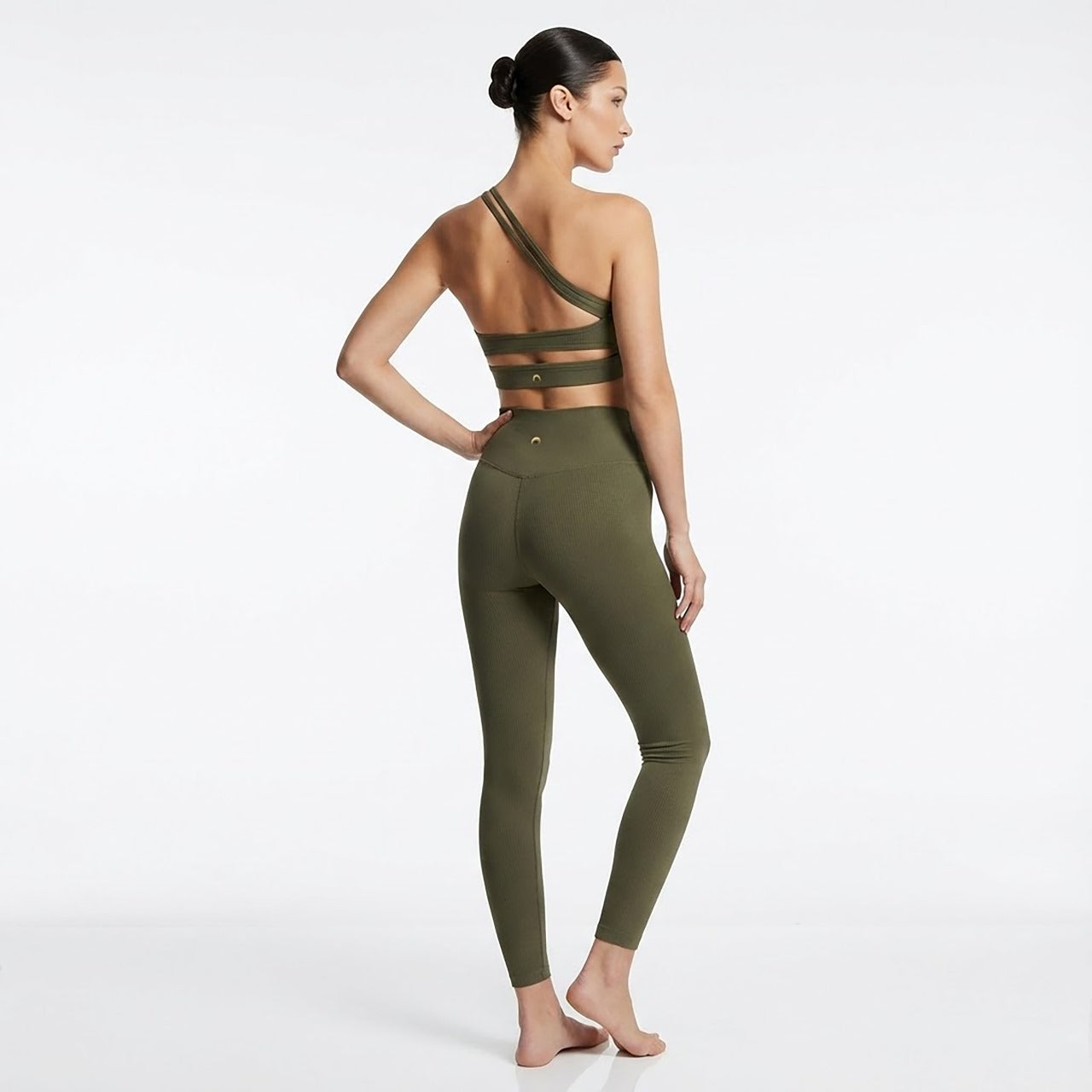 Woman wearing an olive green sports bra and leggings set on a white background