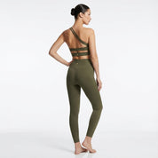 Woman wearing an olive green sports bra and leggings set on a white background