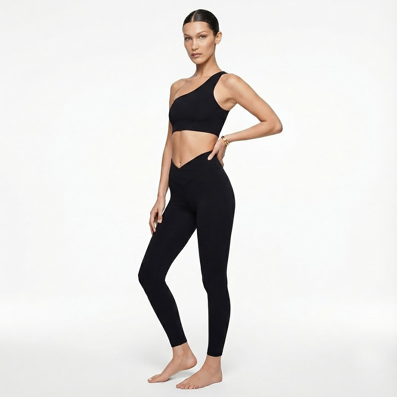 Woman wearing a black sports bra and leggings on a white background