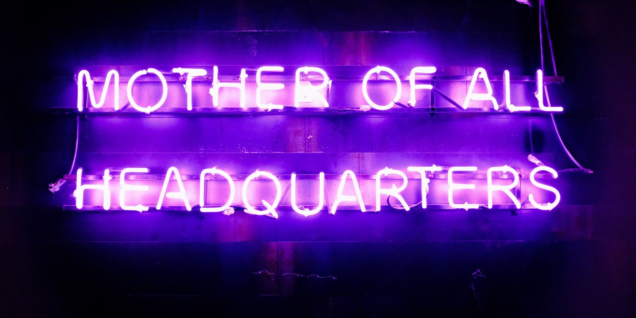 Neon sign in purple saying mother of all head quarters