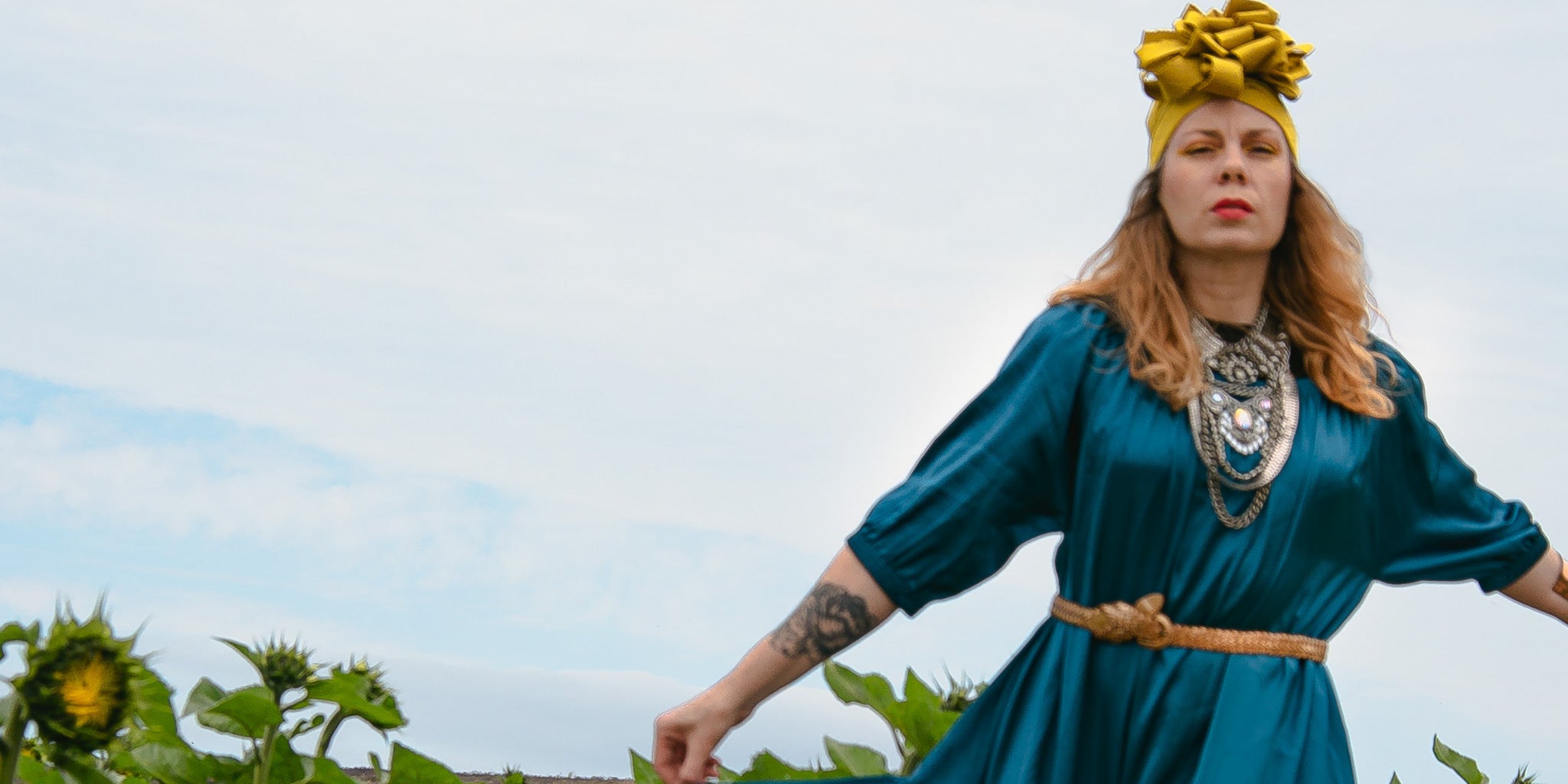 woman in turban standing in sunflower field wearing style ausus in true teal