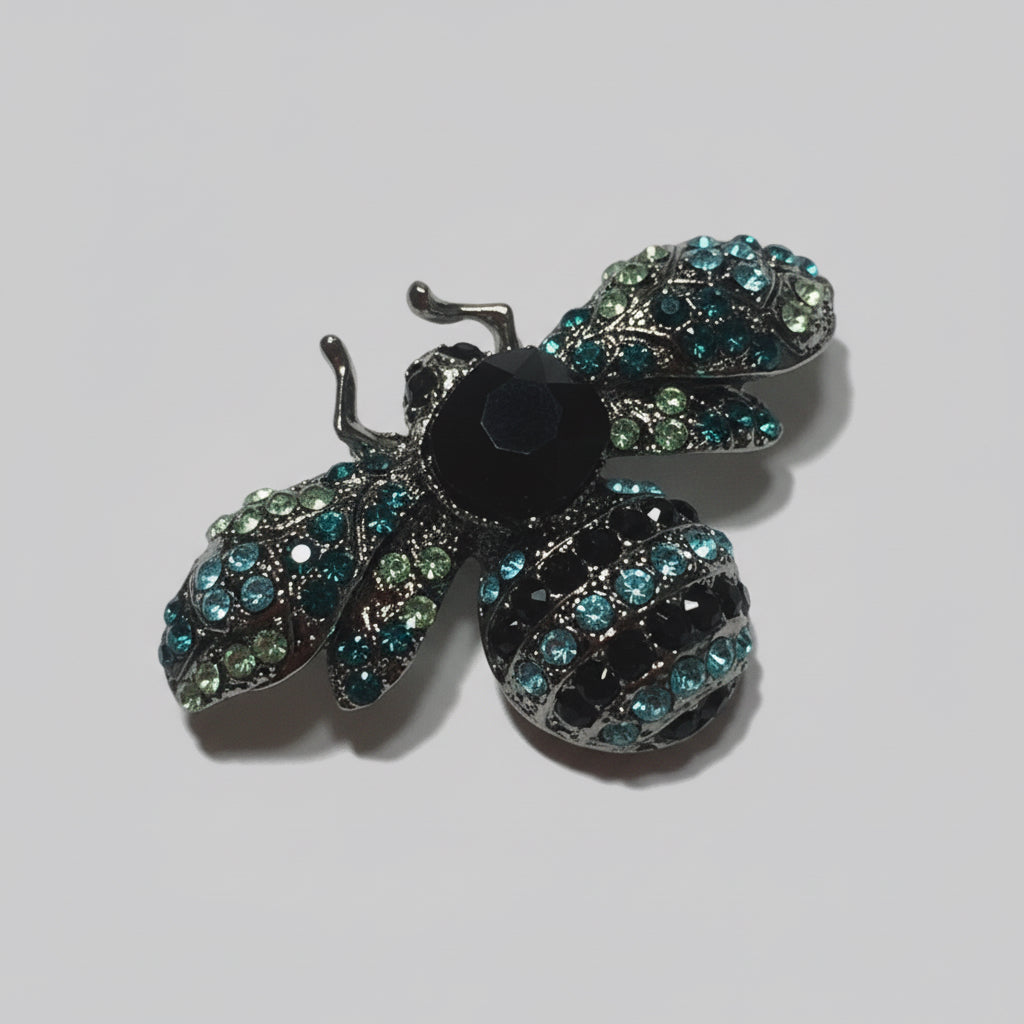 Decorative bee brooch with gemstones on a gray background