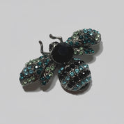 Decorative bee brooch with gemstones on a gray background