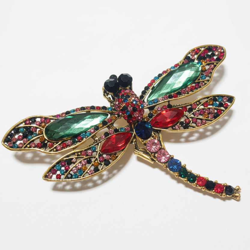 Decorative dragonfly brooch with gemstones on a gray background