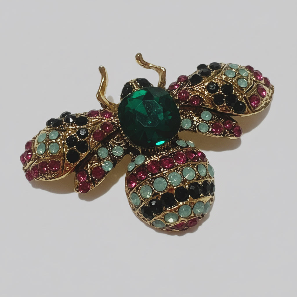 Decorative brooch shaped like a bee with gemstone details on a white background