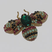 Decorative brooch shaped like a bee with gemstone details on a white background