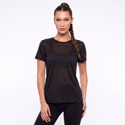 A woman modeling a black short-sleeve athletic t-shirt with sheer mesh panels on the chest and shoulders, paired with black leggings, against a plain white studio background.