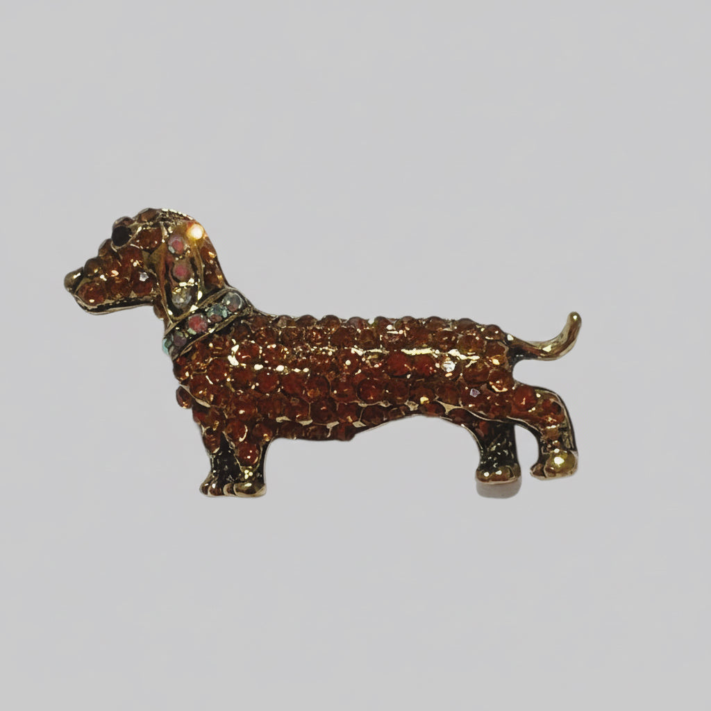 Gold dog-shaped brooch with gemstones on a light gray background