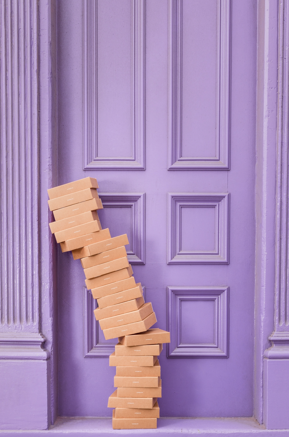 cardboard boxes stacked outside purple door
