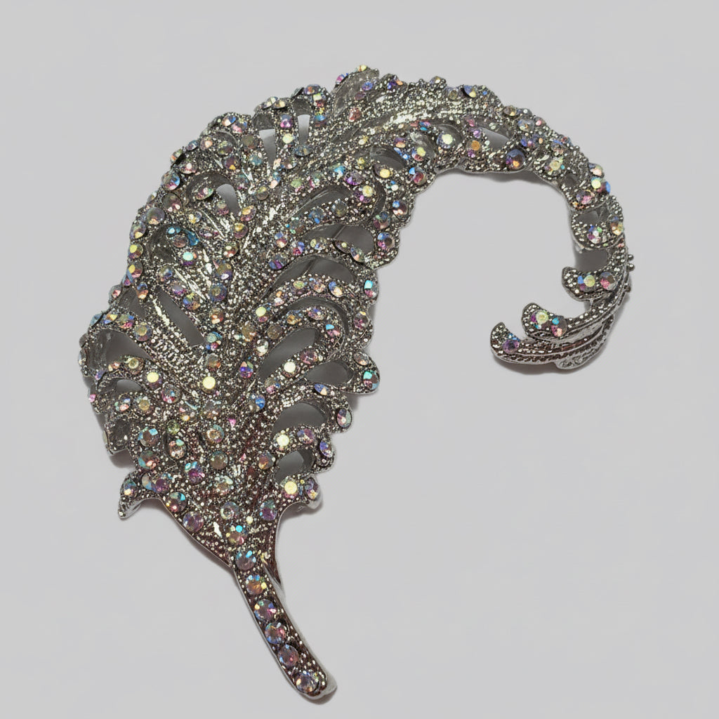Decorative feather-shaped brooch with rhinestones on a gray background