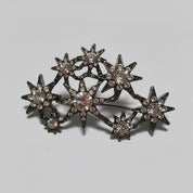 Decorative star-shaped brooch with gemstones on a light gray background