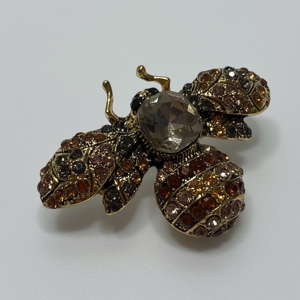 Gold and brown bee-shaped jewelry on a gray background