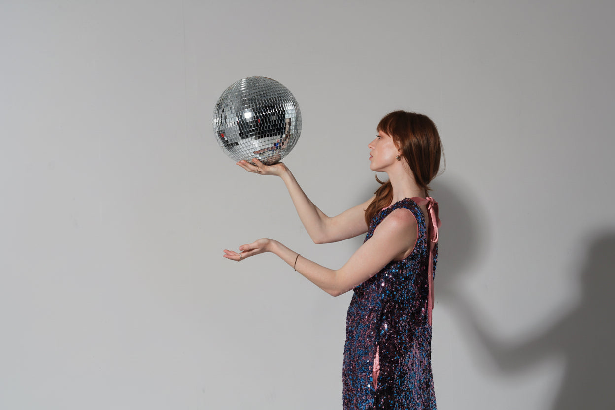 woman holding glitter ball wearing imu shift dress in pink and blue