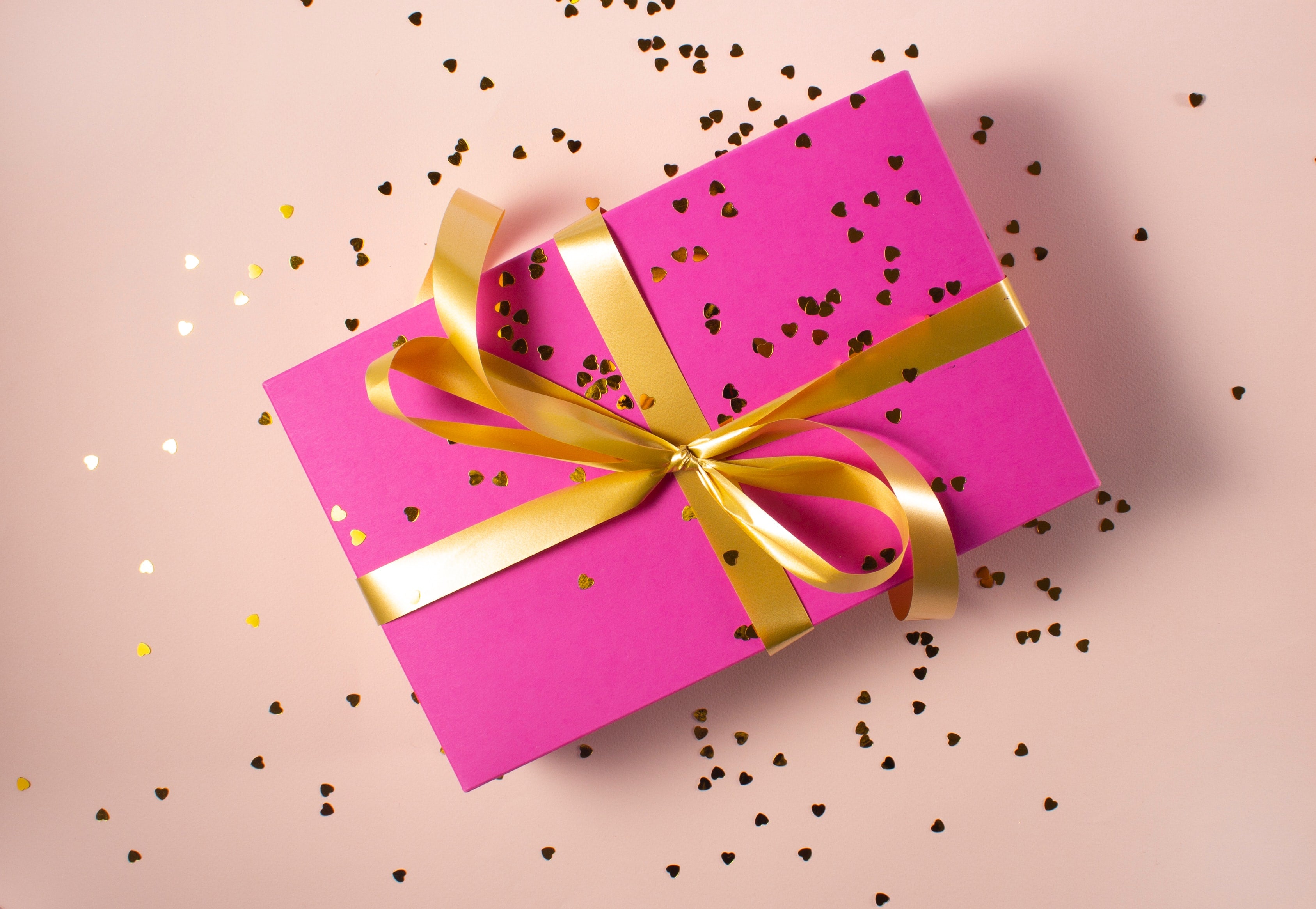 Pink gift box with gold ribbon and hearts